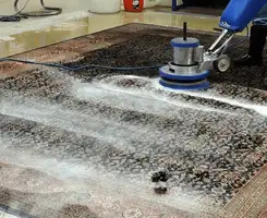 Professional rug cleaning with a rotary floor machine and shampoo foam, deep-cleaning an area rug, in Henderson, NV.